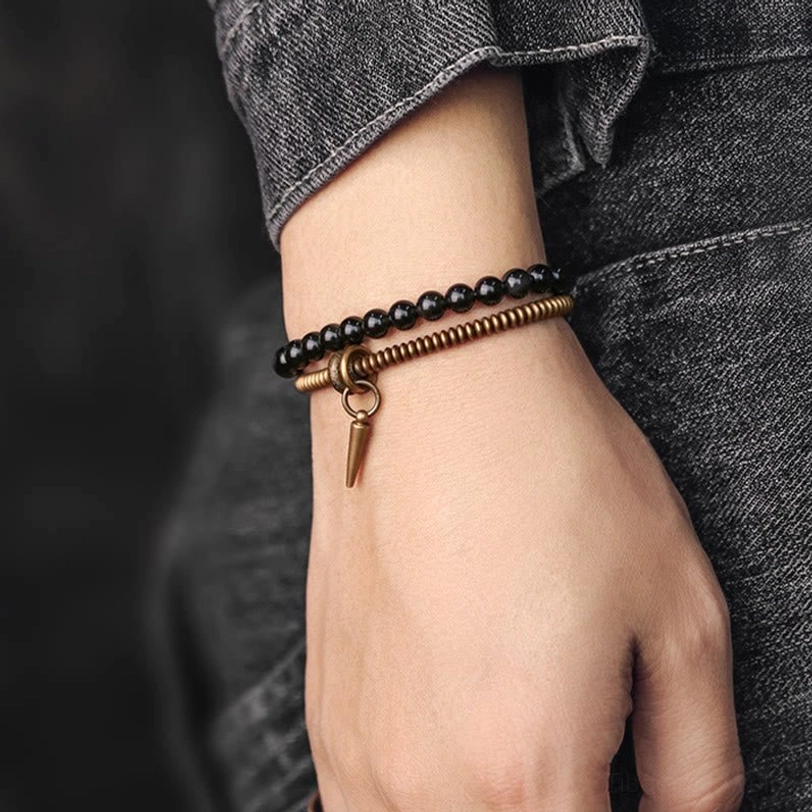 Worn double layer rainbow obsidian bracelet on wrist with denim clothing, lifestyle wear showing layered beads and bronze spike charm