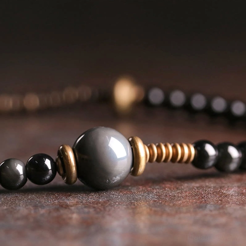 Rainbow obsidian multilayer bracelet showing curved bronze spacers and smooth round black beads in close-up view