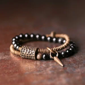 Rainbow Obsidian double layer healing bracelet with antique bronze spike pendant and polished black beads, flat lay overhead view