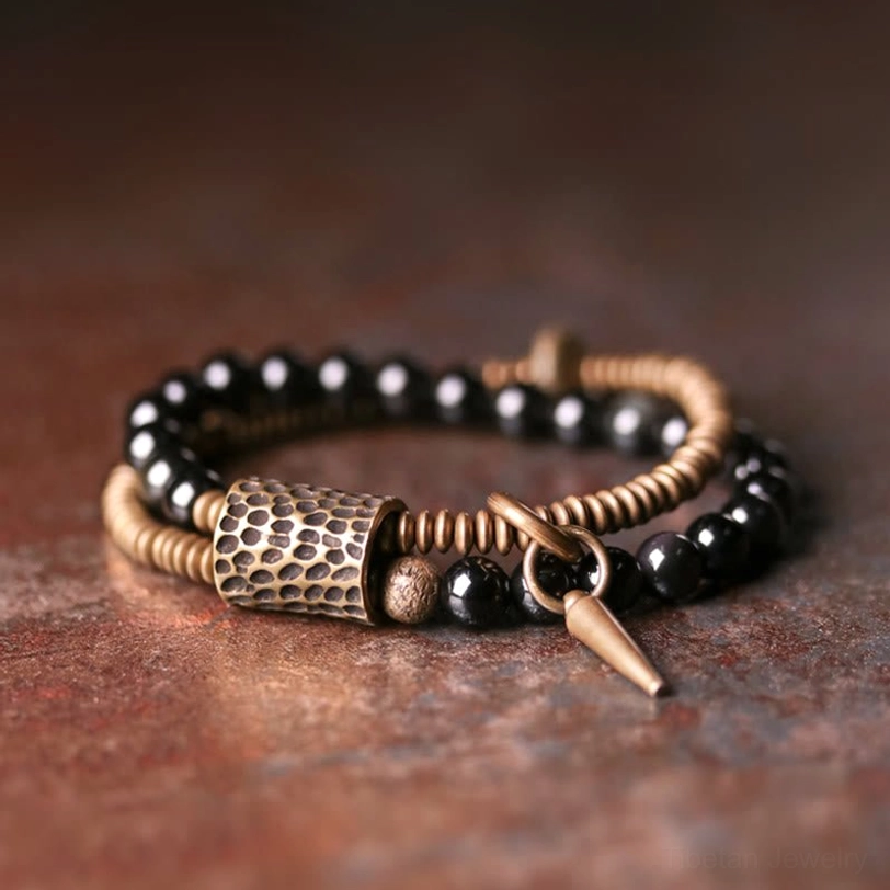 Rainbow Obsidian double layer healing bracelet with antique bronze spike pendant and polished black beads, flat lay overhead view