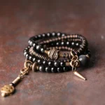 Rainbow obsidian ebony wood copper multilayer bracelet - main product view showing iridescent beads with antique bronze spacers on vintage desktop