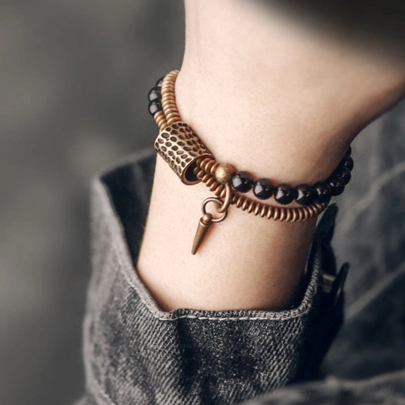 Rainbow Obsidian double layer healing bracelet worn on hand with denim jeans background, front view showing antique bronze hardware and protective spike