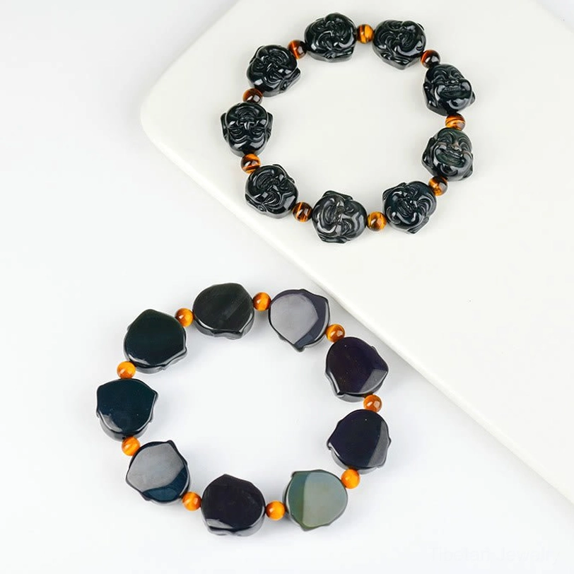 Rainbow obsidian bracelet on white tray - irregular polished black beads with iridescent rainbow sheen and amber spacers