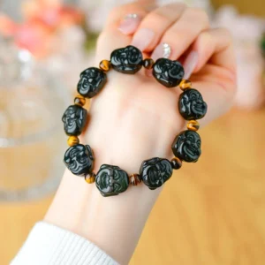 Rainbow obsidian laughing Buddha bracelet worn on wrist - close-up view showing carved Buddha beads with tiger eye amber spacers
