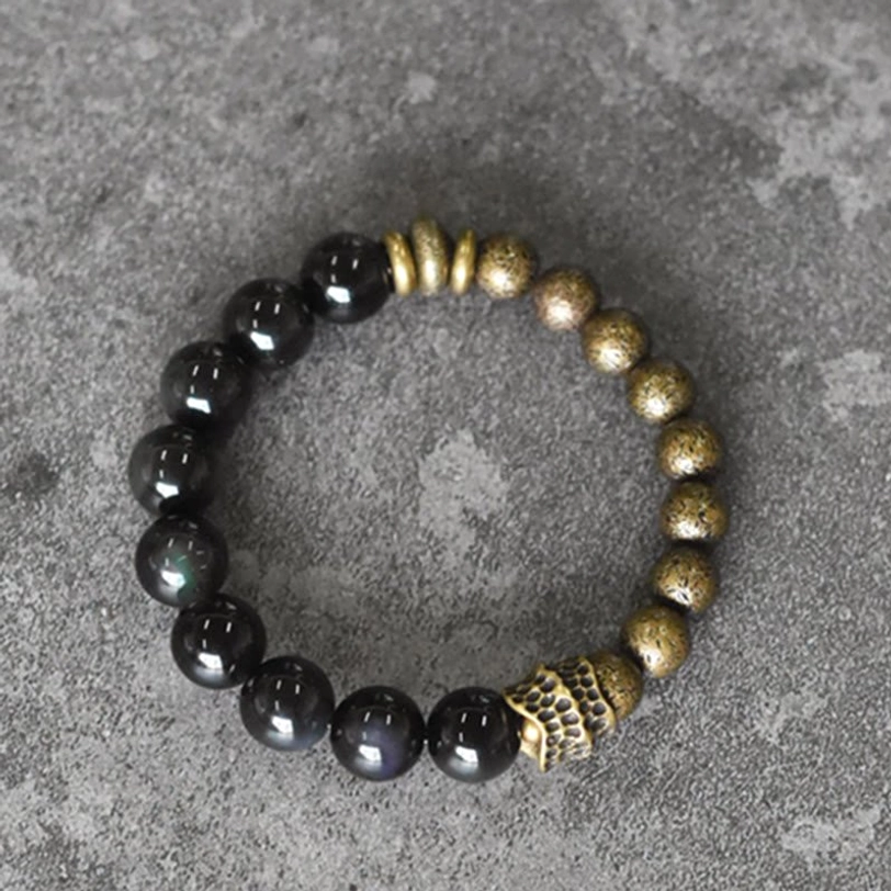 Stretch Beaded Bracelet Overhead View - Mixed Black Obsidian and Antique Bronze Beads with Engraved Metal Spacer Component on Stone Surface
