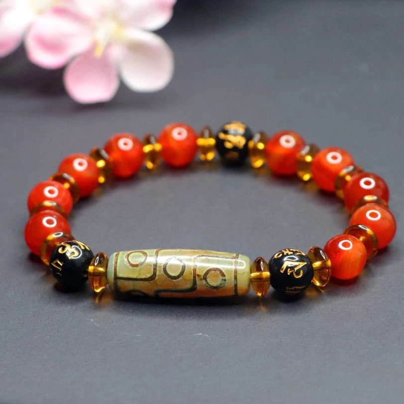 Handmade red agate nine-eye dzi bead bracelet worn on wrist showing comfortable fit and natural color variations of polished agate stones