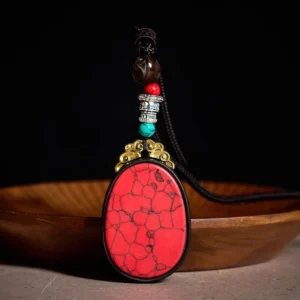 Red ebony wood oval tribal necklace pendant with natural crackling pattern, front view on wooden tray