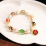 Red God of Wealth Tibetan blessing bracelet with liuli glass beads and incense ash porcelain charm pendant on ceramic tray