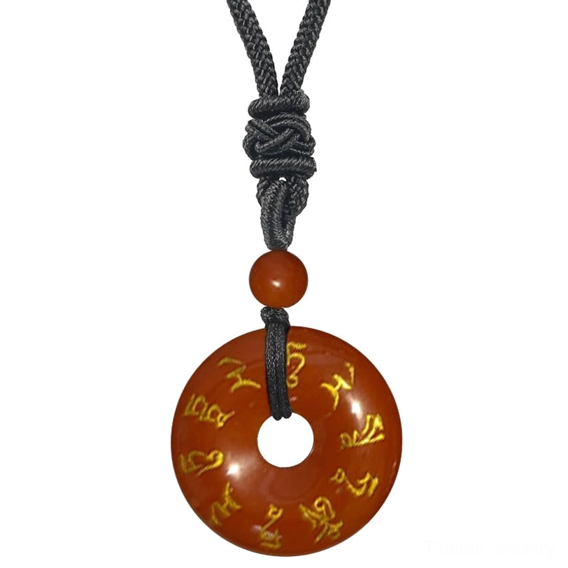 Red Jasper Green Tara mantra necklace pendant close-up, reddish-brown stone with golden Sanskrit engraving and black braided cord