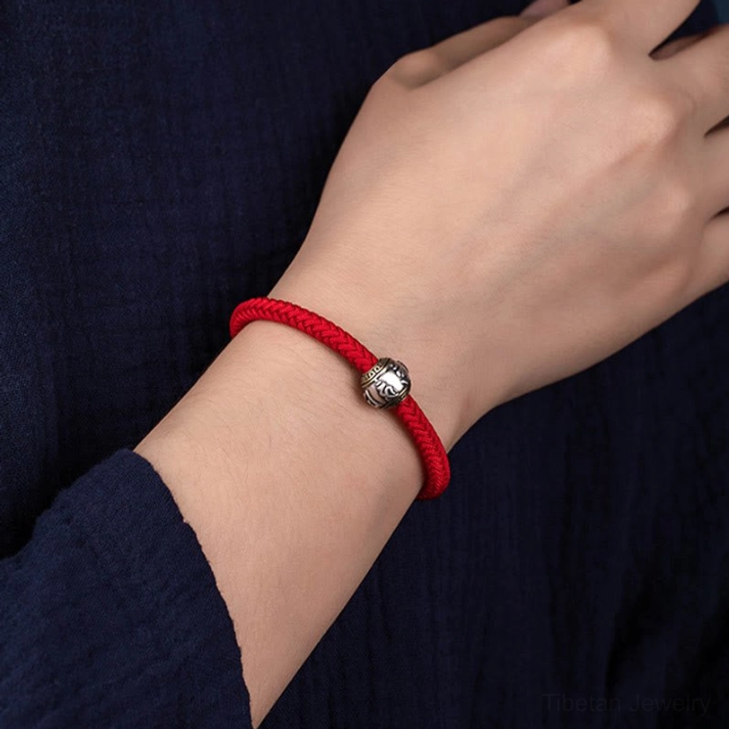 Red Om Mani Padme Hum Tibetan lucky bracelet with woven knot and silver charm detail