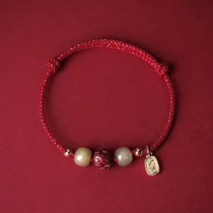 Red silk rope Hetian jade cinnabar lotus lucky bracelet with 14K gold plating, flat lay top-down view