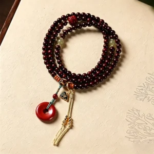 Red sandalwood 108 bead mala with peace buckle on vintage textured paper background, flat lay photography