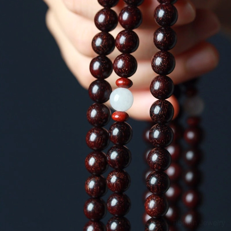 Smooth round red sandalwood beads with white spacer accent held in palm showing craftsmanship and finish