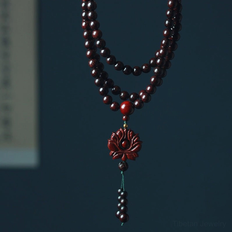 Red sandalwood 108-bead lotus mala bracelet flat lay overhead view with carved lotus pendant on dark background