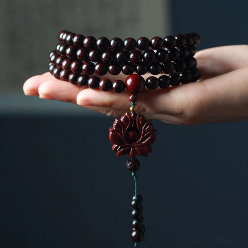 Stacked red sandalwood mala bracelets palm display showing natural wood finish and carved lotus decorations