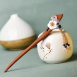 Red sandalwood pink crystal healing hairpin with blue bead tassel displayed on ceramic vessel