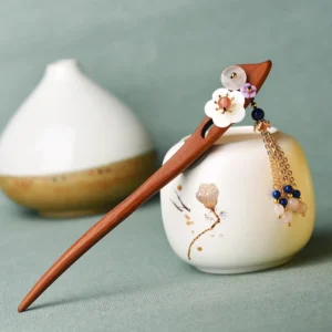 Red sandalwood pink crystal healing hairpin with blue bead tassel displayed on ceramic vessel