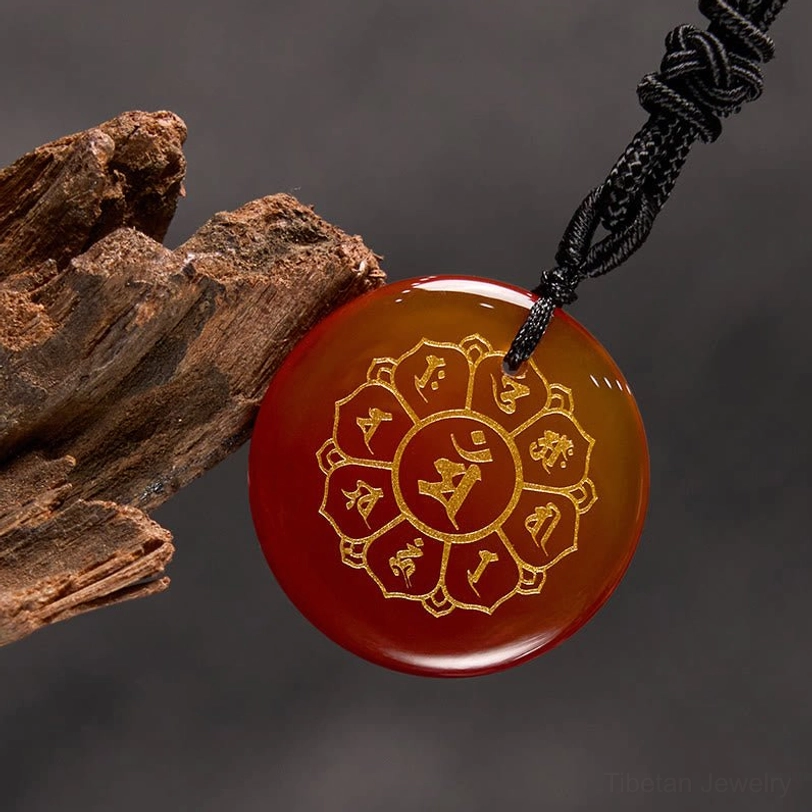 Red Stone Om Mani Padme Hum pendant close-up showing polished surface and Sanskrit engraving