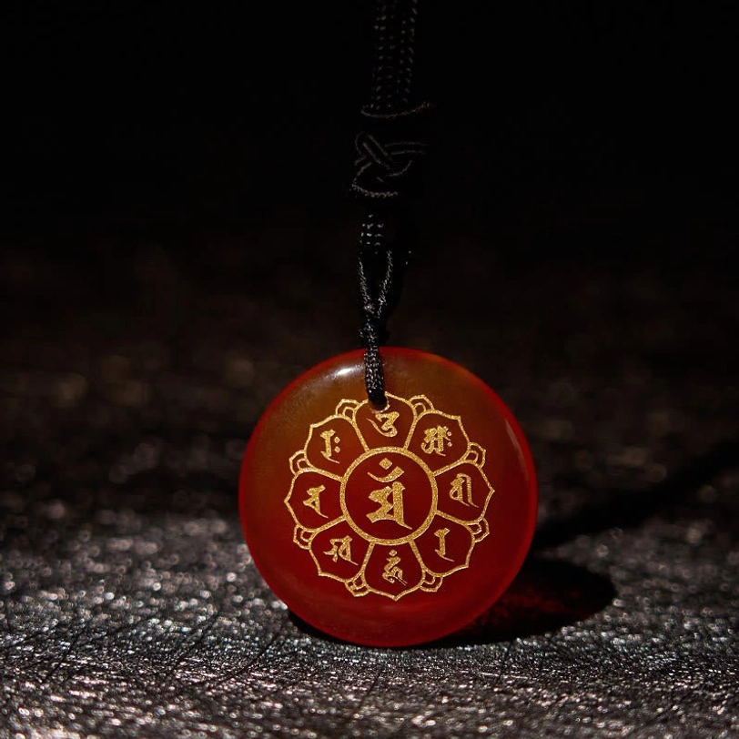 Red Stone jasper tibetan pendant with engraved mantra design on natural background