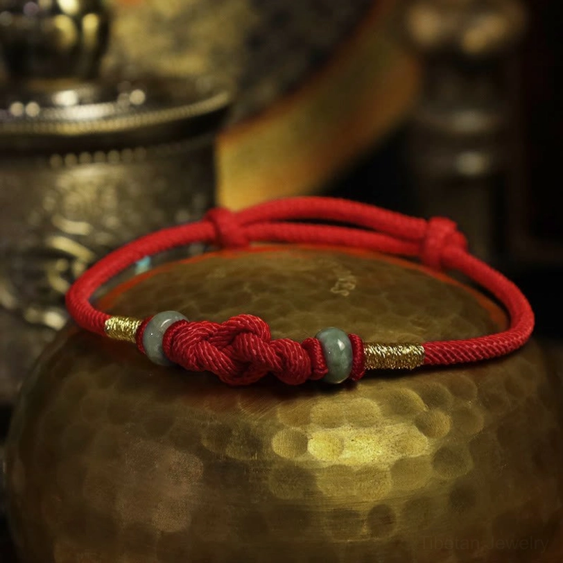 Red string jade bracelet collection display showing multiple hand-braided pieces with natural variations