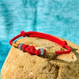 Braided red cord fortune knot with jade beads and gold wrapped sections