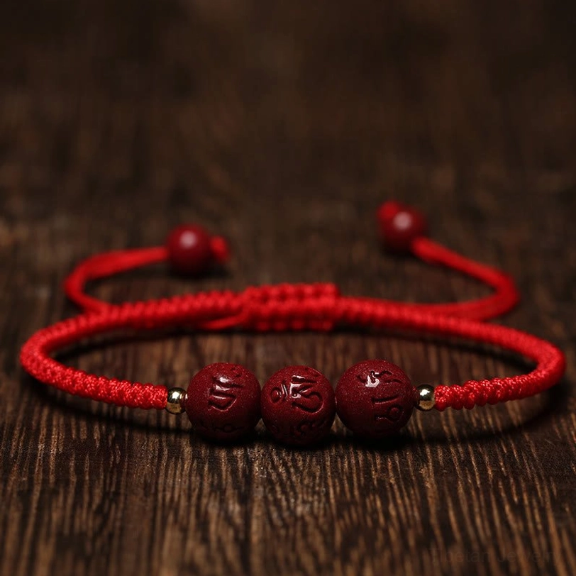 Red string Tibetan protection bracelet with cinnabar Om Mani Padme Hum beads and gold spacer details flat lay