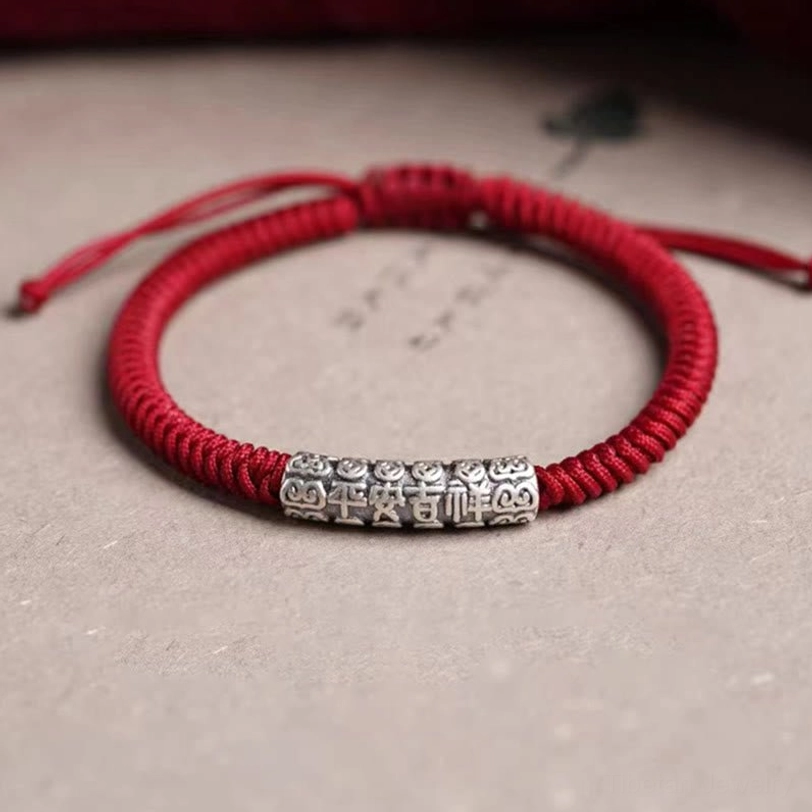 Red woven Tibetan lucky cord bracelet with sterling silver charm showing protective and spiritual energy symbolism