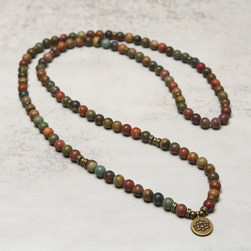 Full length red turquoise 108 bead mala necklace laid out flat with dangling brass lotus pendant