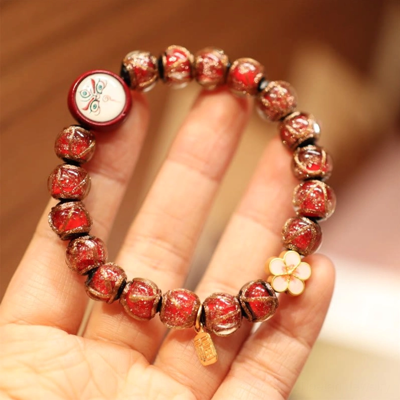 Red White God of Wealth Tibetan bracelet with vibrant beads and prosperity charm pendant close-up detail