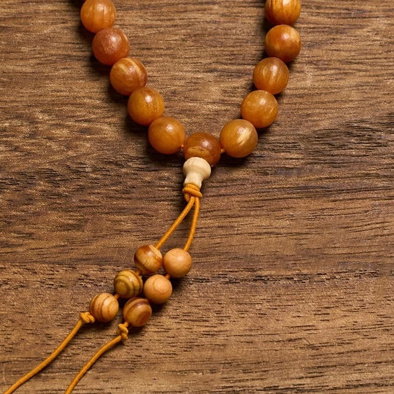 pine wood mala beads close-up showing large smooth individual beads with light-colored guru bead and knotted tassel