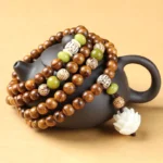 Tibetan rosewood lotus mala bracelet with 108 beads, 6mm 7mm 8mm sizes, displayed in flat lay with black ceramic teapot and wooden details