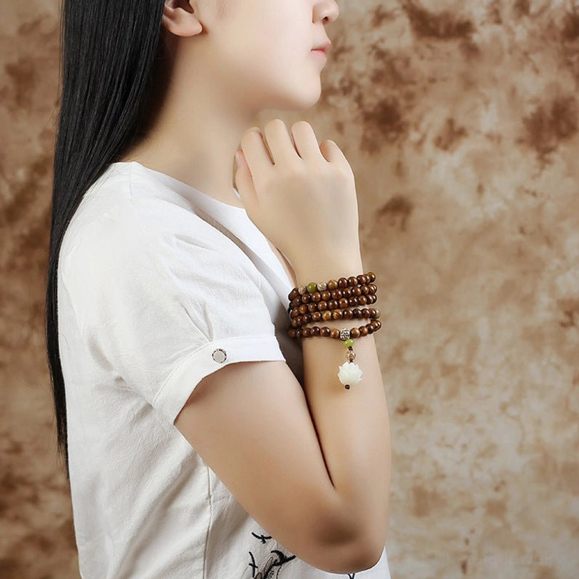 Stacked rosewood mala bracelets worn on wrist showing multi-layer design with lotus charm, worn styling inspiration