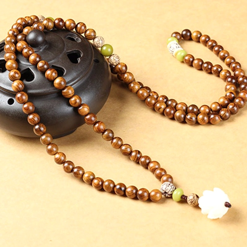 Full-strand rosewood lotus mala necklace with white pendant displayed against black incense burner, side angle view