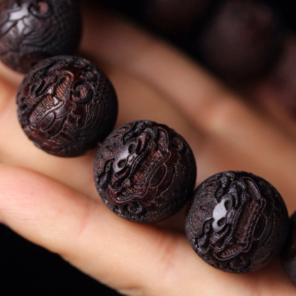 Rosewood Pixiu bracelet bead close-up on palm displaying detailed wood engraving