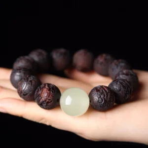 Close-up rosewood Pixiu bracelet on palm showing detailed wood carving and jade accent bead