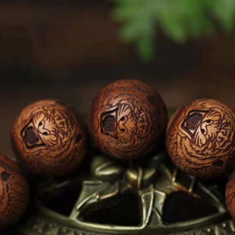 Flat lay close-up of tiger engraved rosewood beads showing detailed carved tiger head patterns and natural dark brown wood grain texture