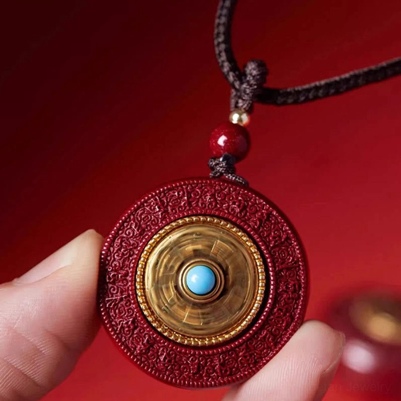 Rotating Cinnabar Om Mani Padme Hum Pendant Being Held - Showing Turquoise Inlay and Red Stone Detail