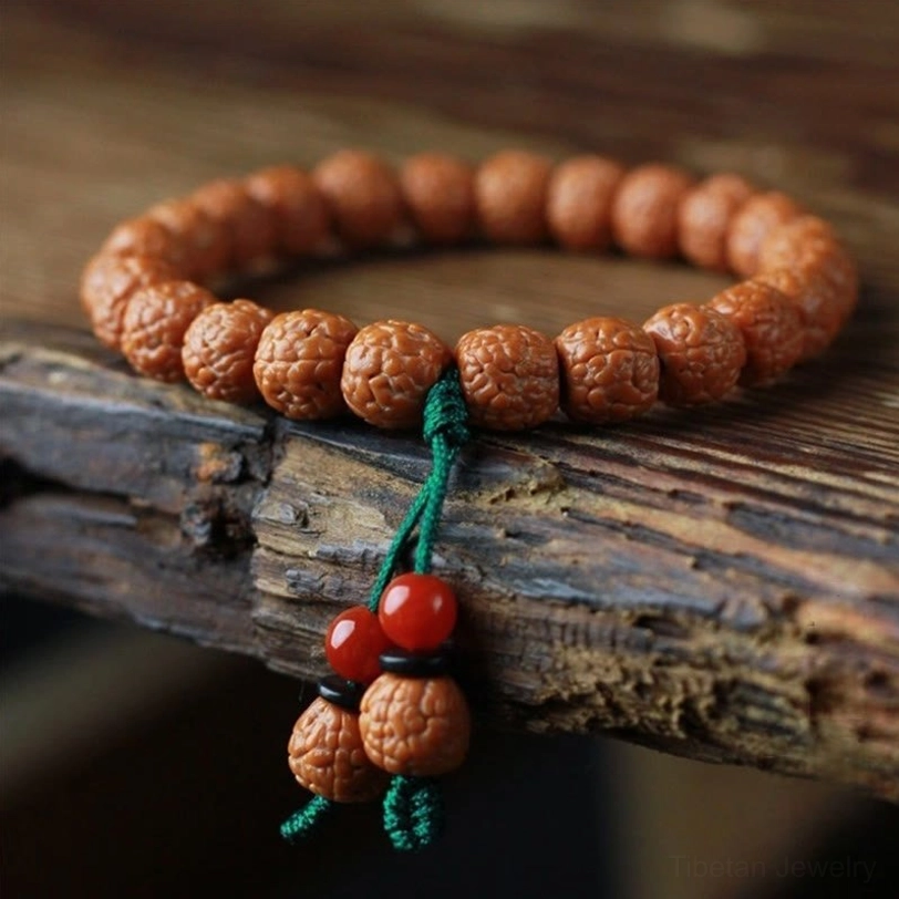 Rudraksha bodhi seed wealth bracelet with red agate tassel close-up view on wooden surface