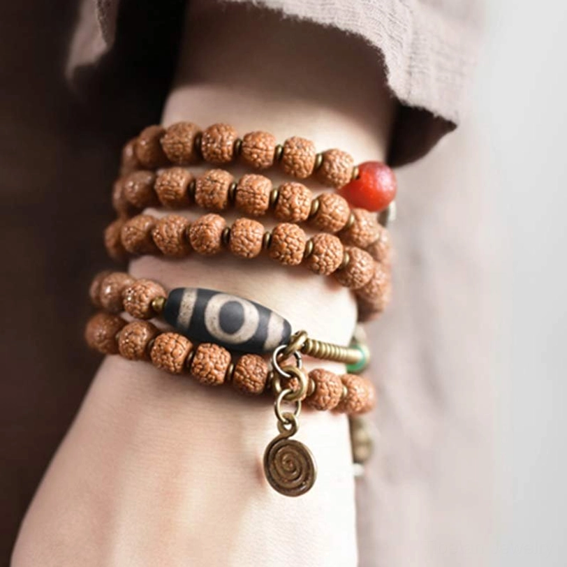 Layered Rudraksha Mala Bracelets worn on wrist showing multi-loop styling with Nine-Eye Dzi Bead and spiral tassel detail
