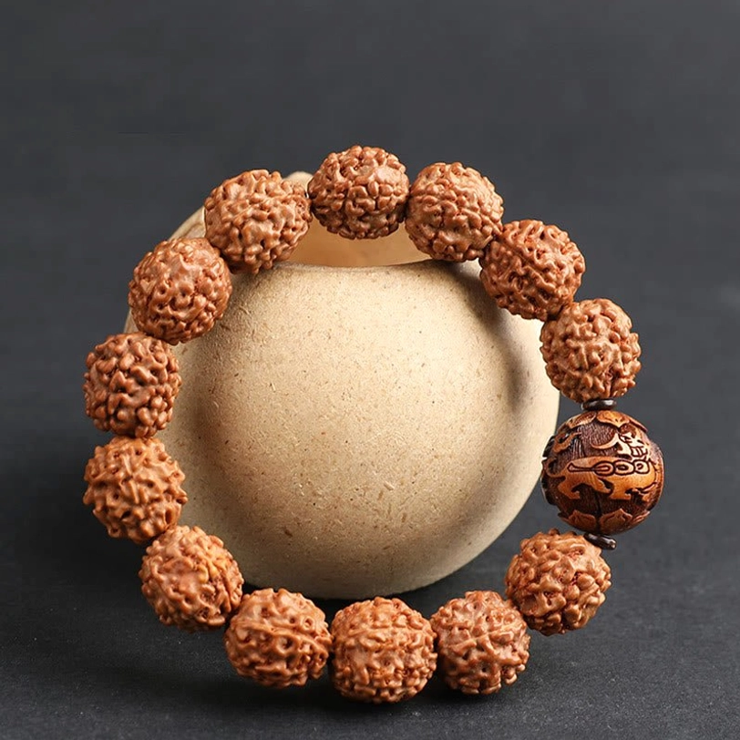 Rudraksha Pixiu bracelet circular arrangement in beige ceramic container, dark background, overhead view