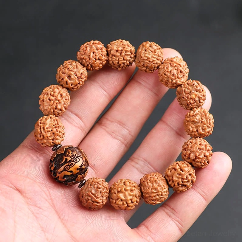 Rudraksha Pixiu wealth bracelet held in palm, brown textured beads with carved wooden Pixiu accent bead on dark background