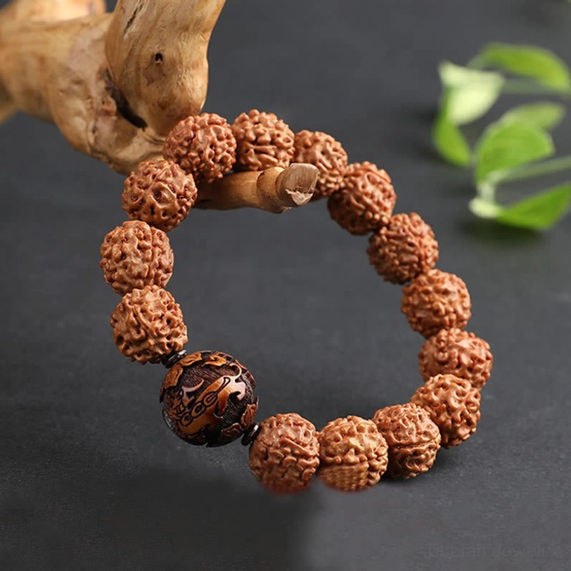 Rudraksha Pixiu bracelet side view with wooden ornament and green leaves, textured brown beads with dark focal bead