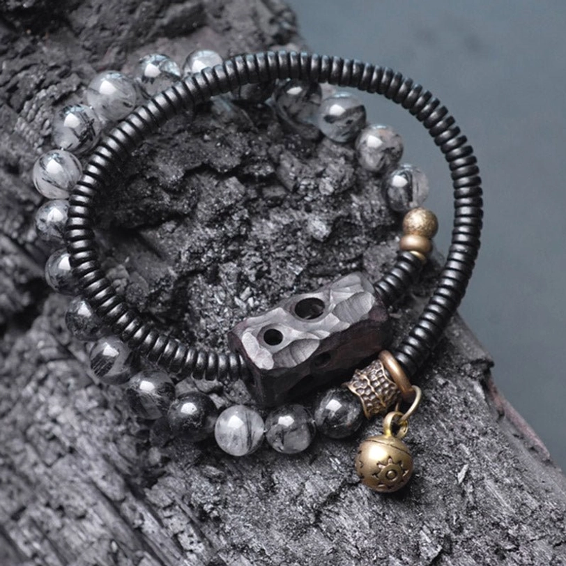 Top-down flat lay of black rutilated quartz beads with ebony wood spacer and brass bell charm