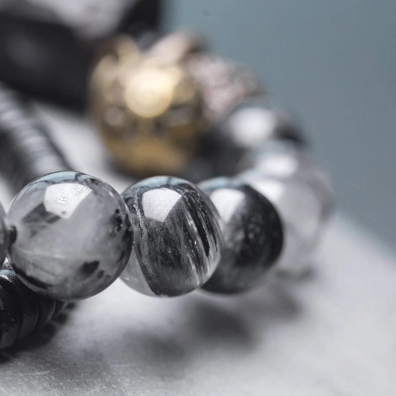Macro close-up of black rutilated quartz showing natural inclusions and metallic spacer beads