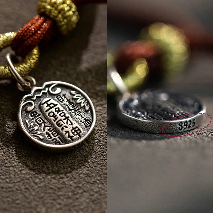 Macro close-up of sterling silver prosperity bracelet charm showing S925 hallmark, engraved design, and braided cord texture