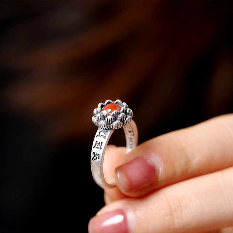 Red agate lotus ring displaying spiritual design and adjustable silver band detail