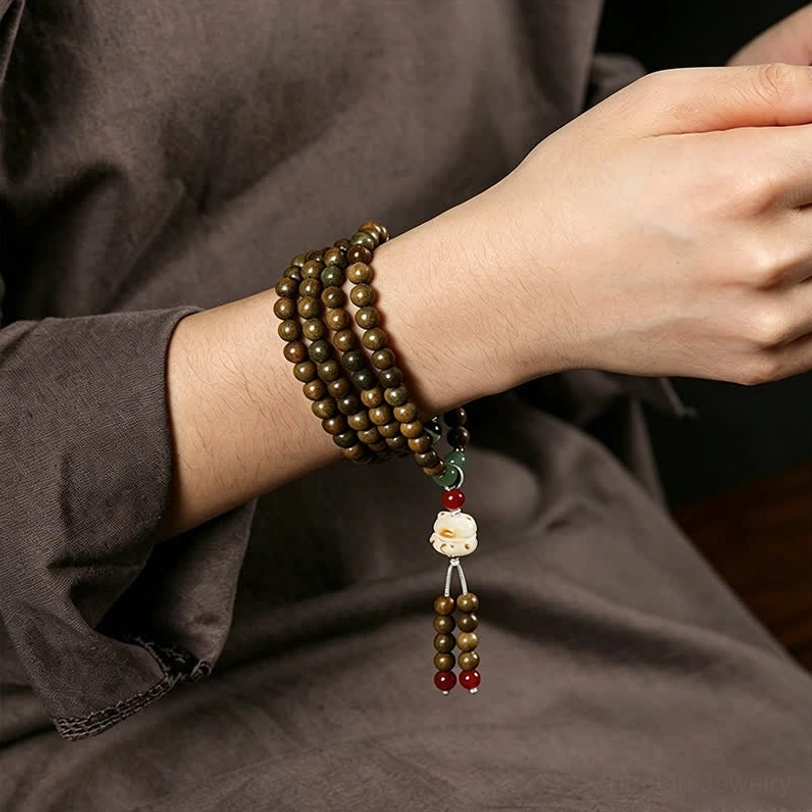 Green sandalwood cat charm mala worn on wrist showing multi-wrap style with tassel pendant detail