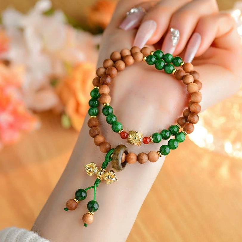 Sandalwood healing bracelet on human wrist with tibetan vajra charm against floral background