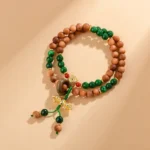 Sandalwood Dorje Vajra bracelet with green jade beads and gold charm flat lay overhead view