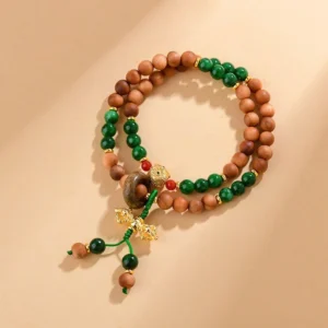 Sandalwood Dorje Vajra bracelet with green jade beads and gold charm flat lay overhead view